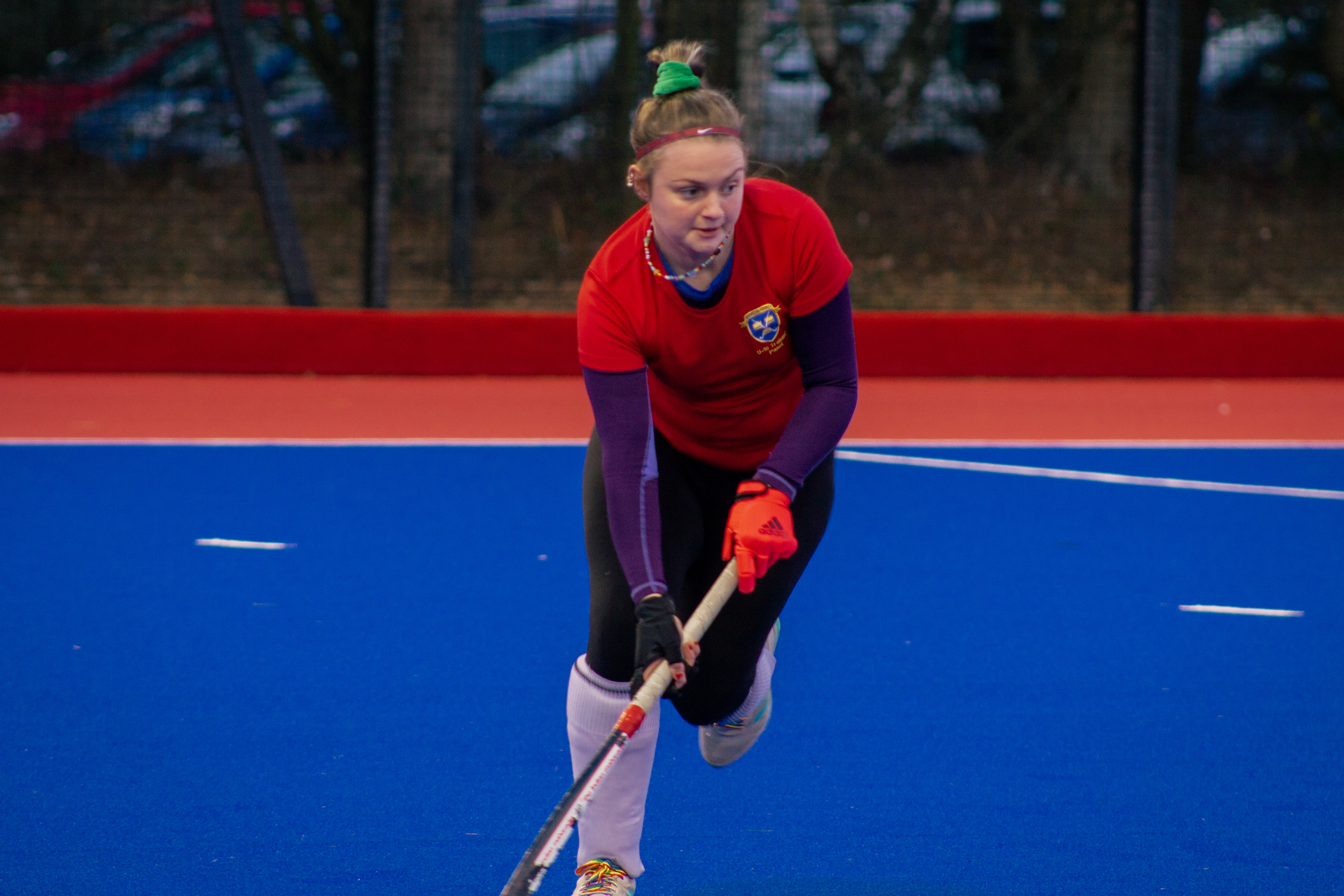 Woman in a red t-shirt in action playing hockey