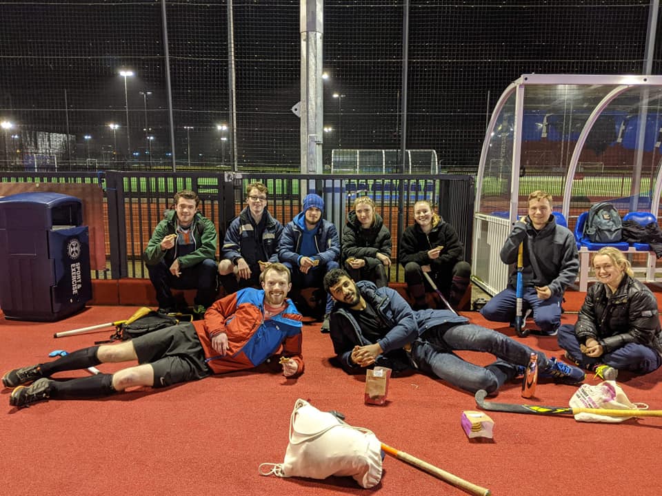 Engineers hockey posing for a photo at the edge of a red hockey pitch