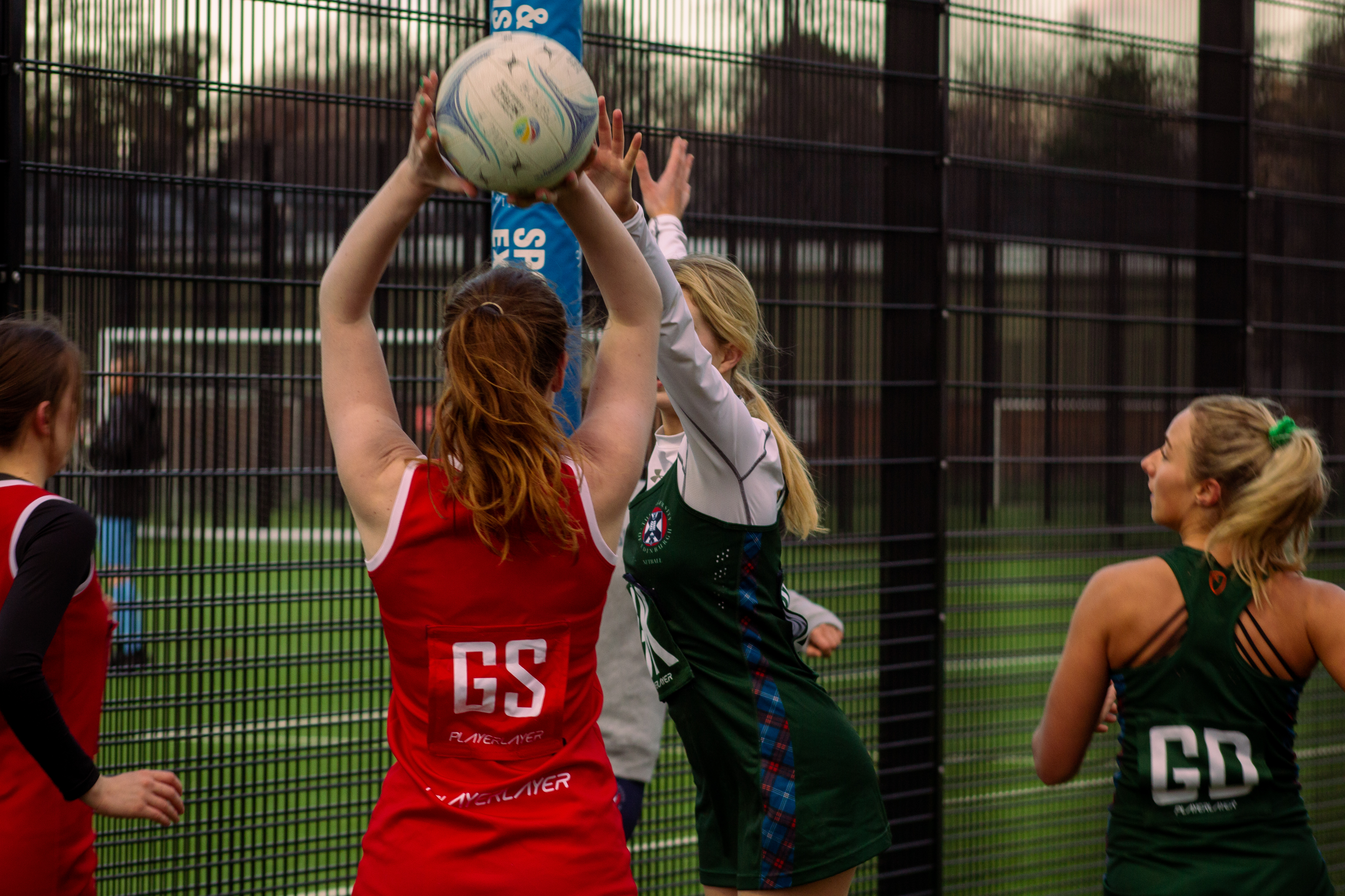 Netball players playing on an outdoor court.