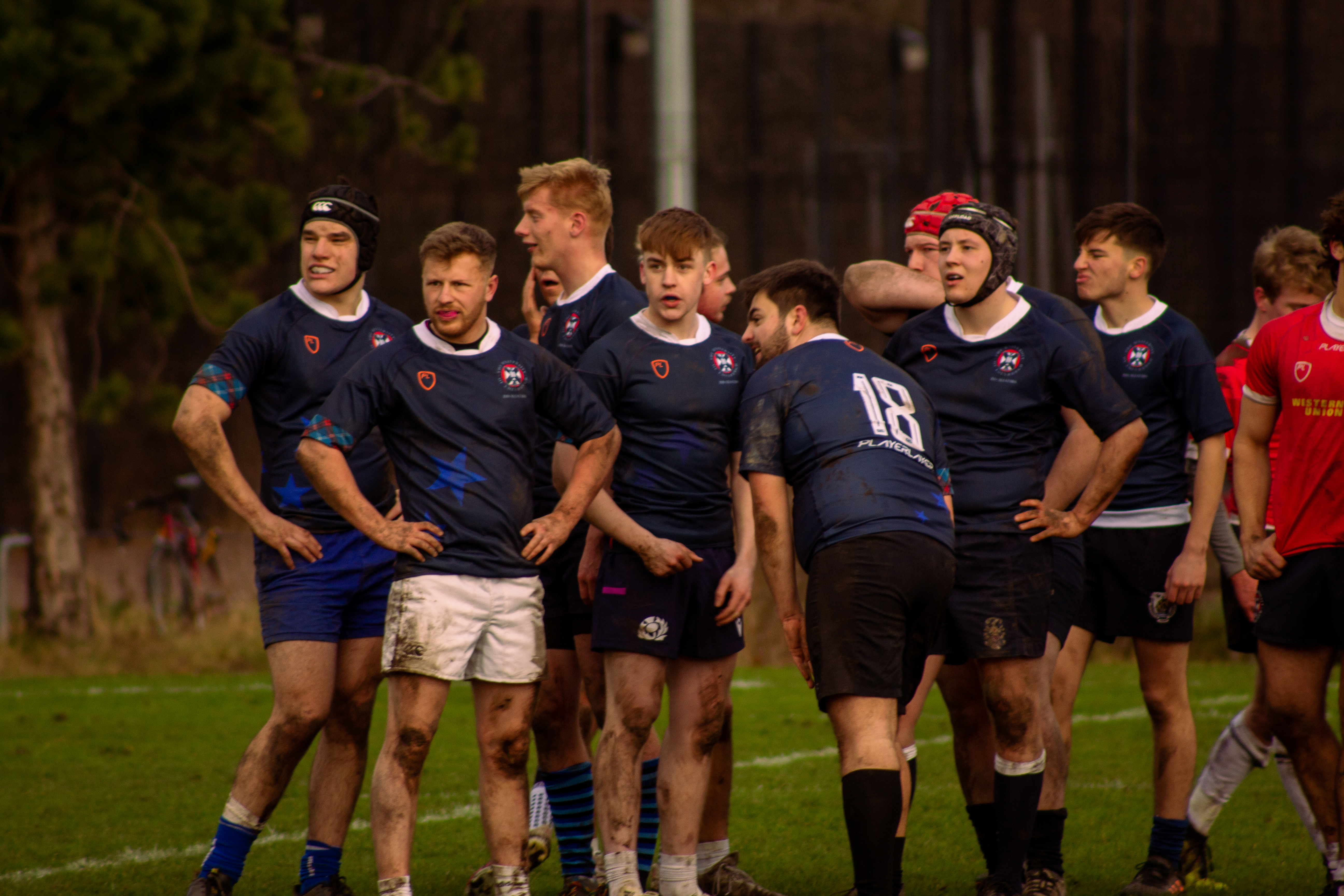 Intramural all-stars rugby team wearing dark blue shirs standing together looking at something behind and to the left of the camera
