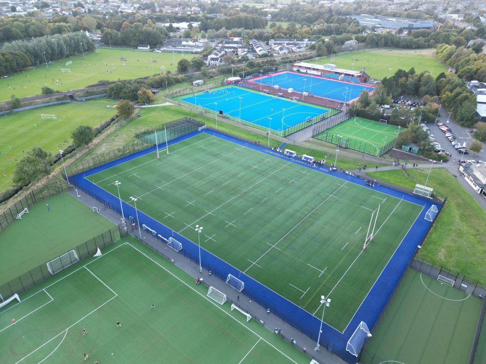 Arial view of Peffermill Playing Fields, with multi purpose astro in central focus. In the foreground grass football pitches can be seen. In the background hockey pitches, MUGAS and grass pitches can be seen. 