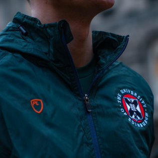 Close up image of forest green rain jacket, featuring the University of Edinburgh roundel and the PlayerLayer logo